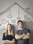 Couple under drawing of house looking perplexed.