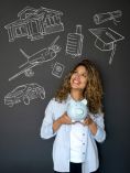 Woman standing in front of chalkboard that has pics of an airplane, graduation cap, car, house and more.