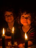 Kids in the dark with candles in front of them.