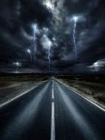 Road with dark clouds above and lightning in the distance.