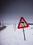 Caution: Slick Road sign on a snowy road.