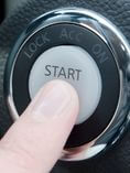 Person pressing Start ignition button in car