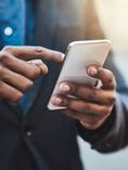 Man holding cell phone while on the go.