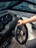 Hand on boat steering wheel.