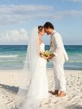 Bride and groom holding hands on a beach.