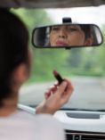 Woman putting lipstick on while driving.