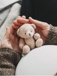 Pregnant woman holding teddy bear in front of her belly.