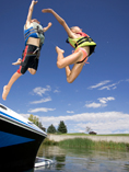 Kids jumping off dock into a lake.