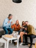 Group of people sitting close together on a sofa while eating and talking.