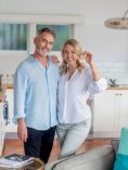 Middle-aged man and woman standing in apartment holding keys.