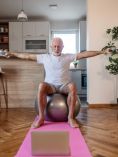 Older man doing yoga in small apartment.