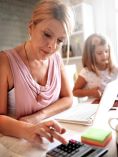 Mom paying bills with daughter in background.