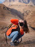 Girl with camera in mountainous desert region.