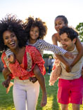 Mixed race family--parent and two kids--playing in park.
