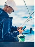 Man on boat typing in cell phone.