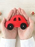 Person holding red toy car in hands