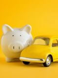 Piggy bank and toy car on yellow background