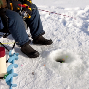 Man ice fishing on a sunny day.