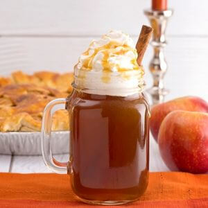 Photo of a cup of hot caramel cider with whipped cream on top 