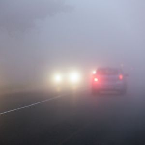 Cars driving in heavy fog at dusk.