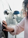 Woman examining damage to car.